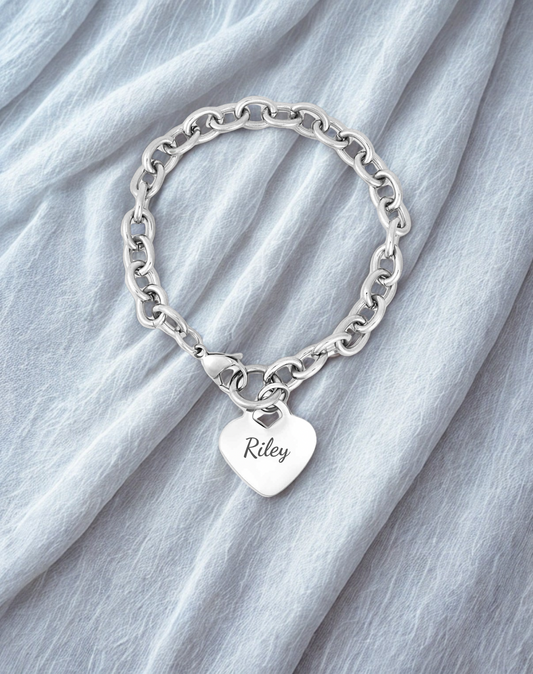 Silver bracelet with a heart-shaped tag on a light gray fabric background
