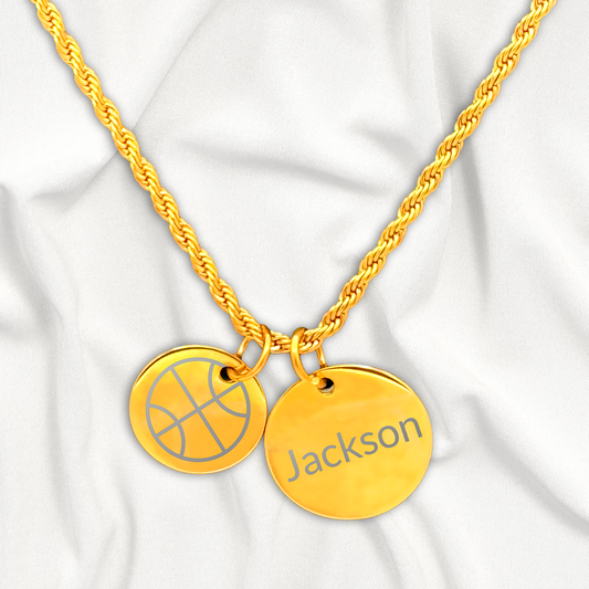 Gold necklace with basketball charm and 'Jackson' pendant on a white fabric background