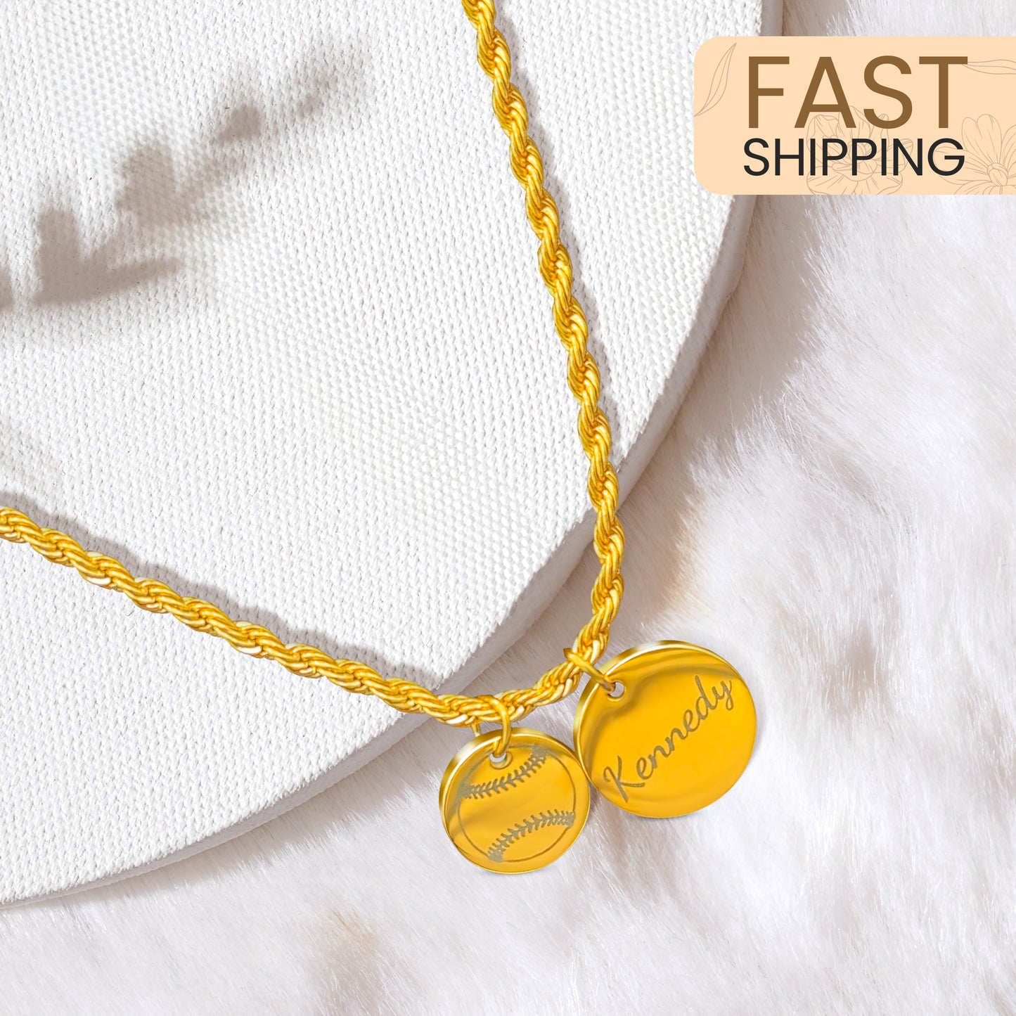 Gold two rope necklace with two charms, one with image of a softball, the other with the name "Kennedy" on a white background with the words "Fast Shipping" above it.