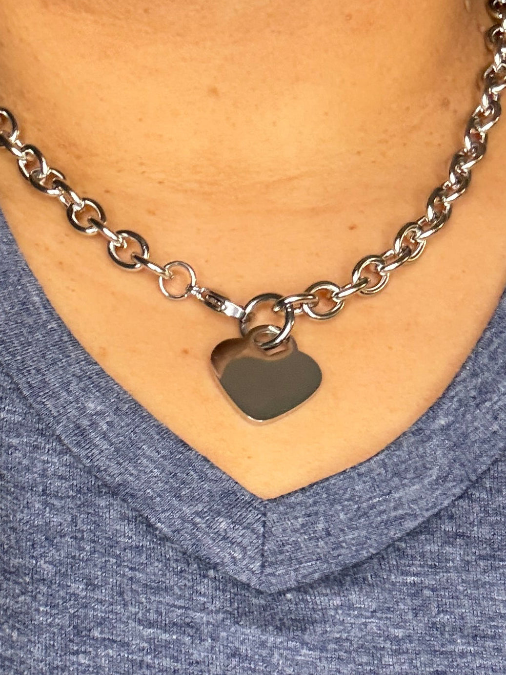 Person wearing a silver chain bracelet on an arm with a blue sleeve.