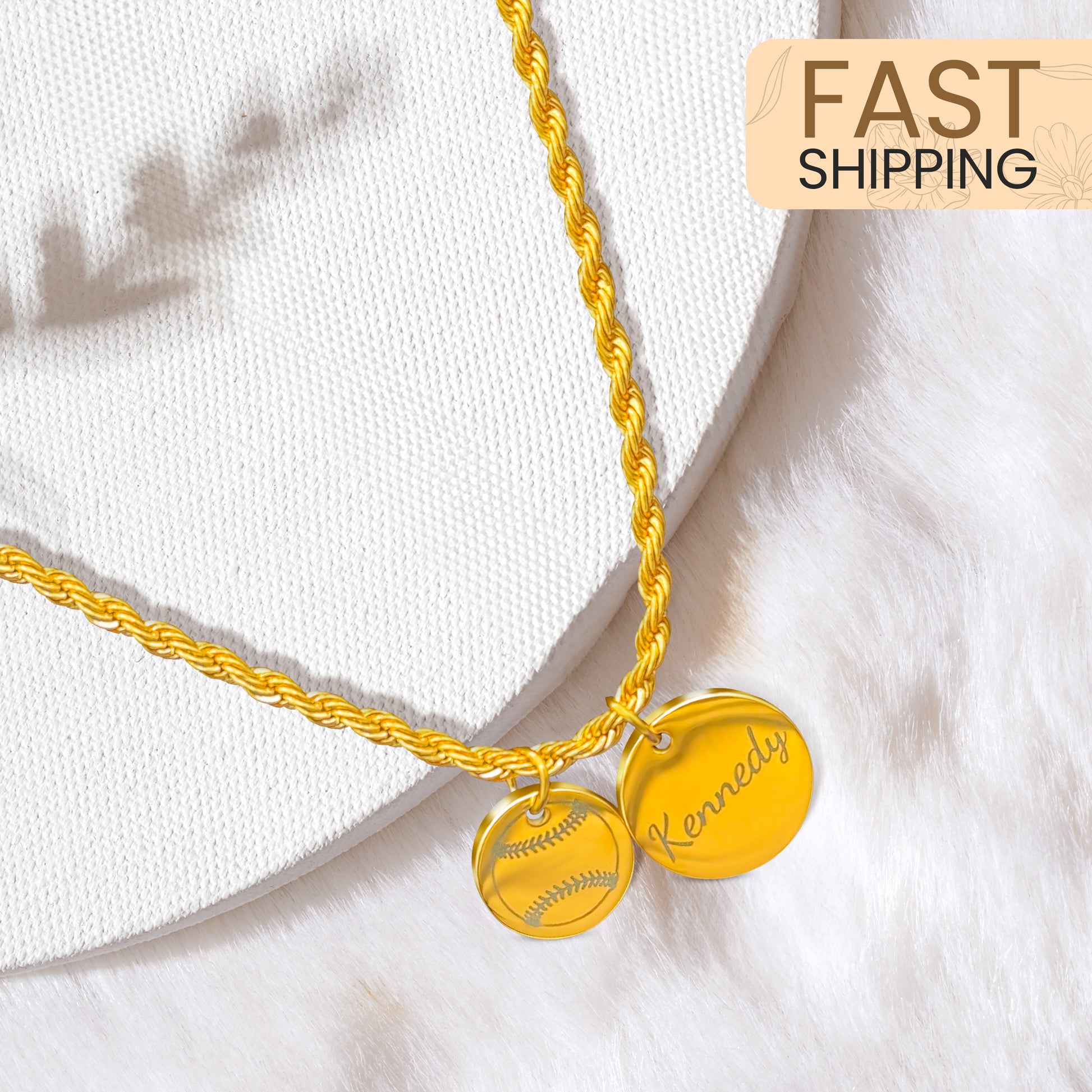 Gold two rope necklace with two charms, one with image of a softball, the other with the name "Kennedy" on a white background with the words "Fast Shipping" above it. 