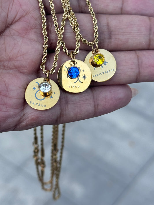 hand holding three horoscope necklaces with birthstone charms